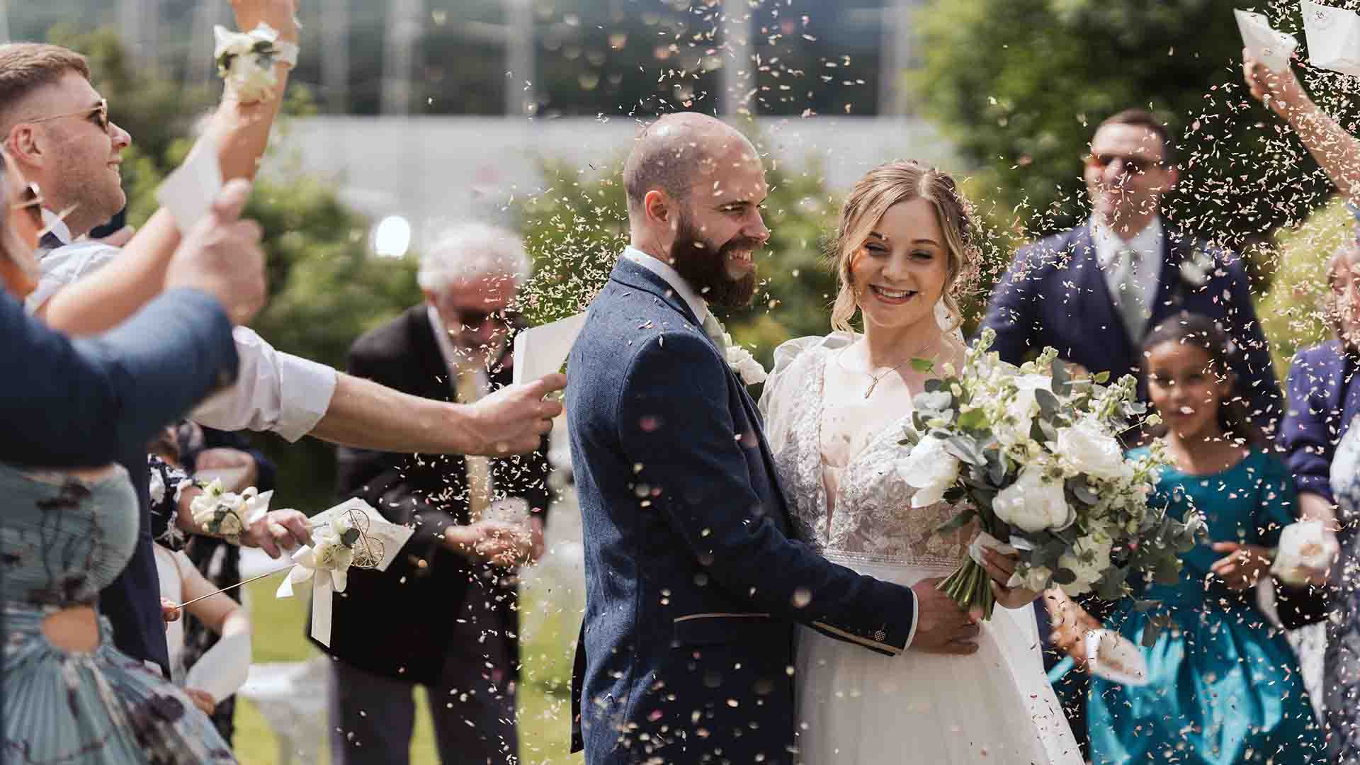 Newly weds on the hotel lawns with confetti thrown over them.
