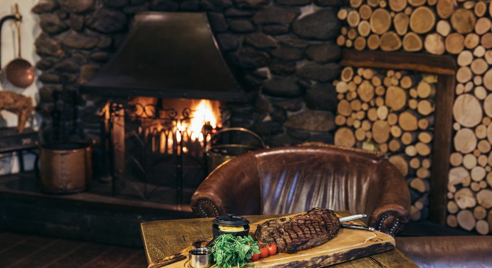 Enjoy steak by a cosy fireside table in the lounge - The Wild Boar