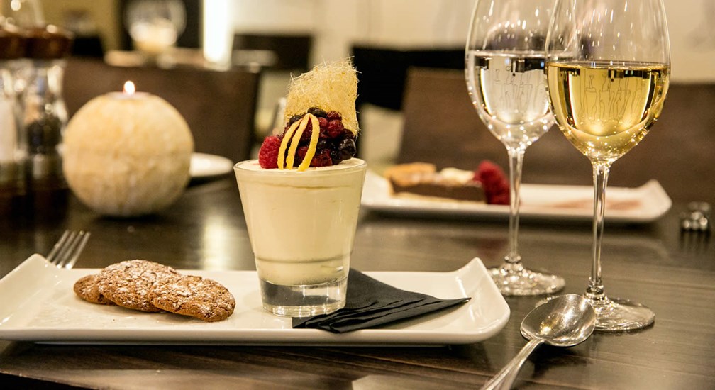 White mousse with red berry fruits and spun caramel and 2 glasses white wine