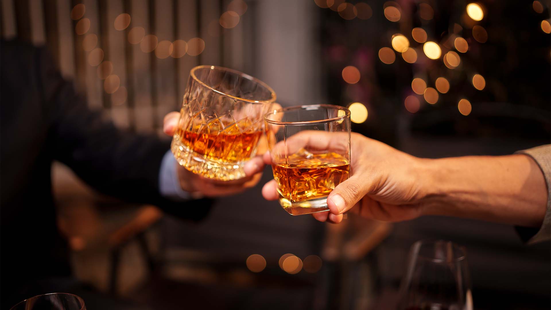 Two glasses of whisky being chincked together