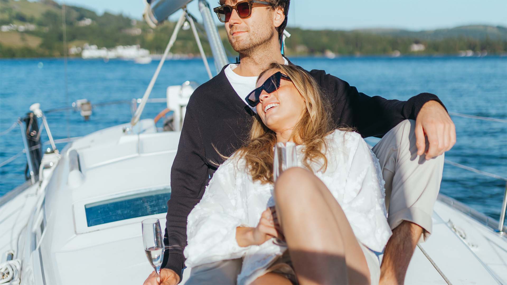 Couple sat relaxing on the deck of a chartered yacht sailing on lake Windermere