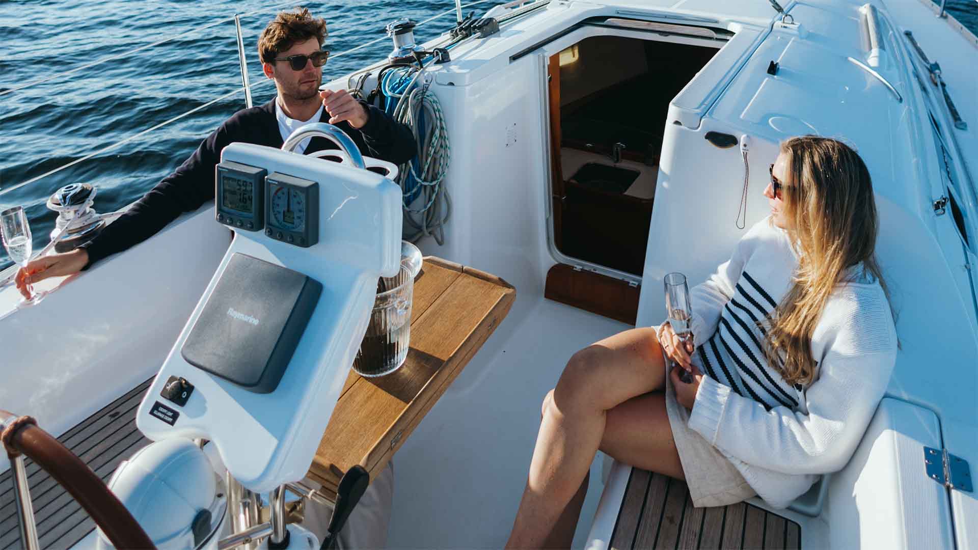 Couple sat relaxing on the deck of a chartered yacht sailing on lake Windermere