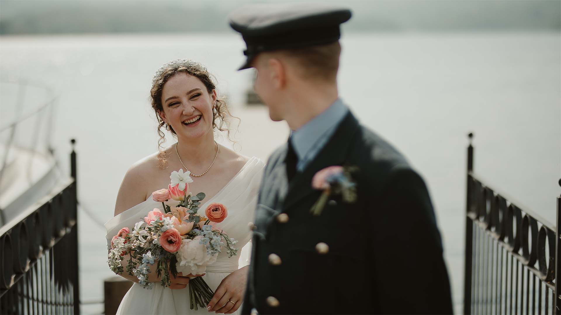 Newly married couple stood on the hotel jetty overlooking lake Windermere