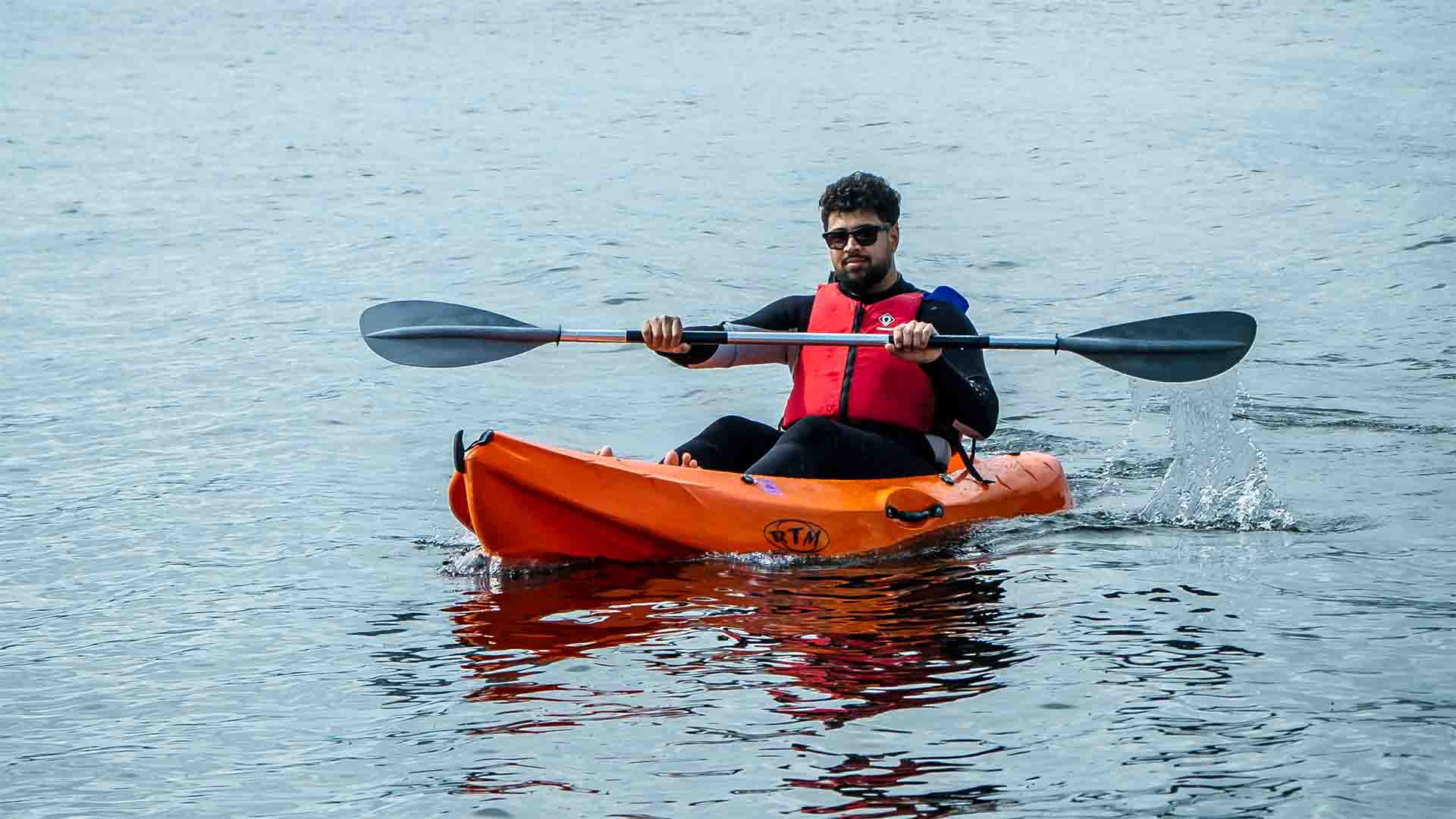 Young man sat atop a hired sit-on-top kayak, out on lake Windermere