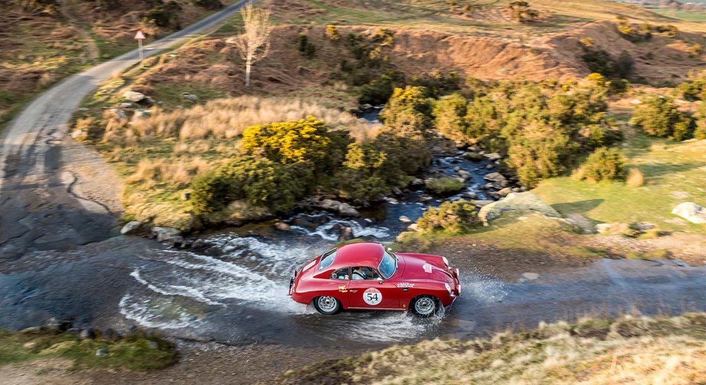 Red Porsche 356B exiting a shallow ford