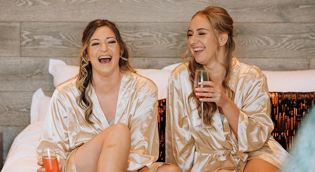 Two women sat laughing on bed