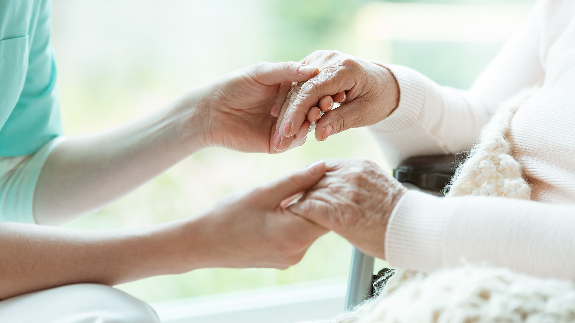 A carer holding the frail looking hands of an elderly woman