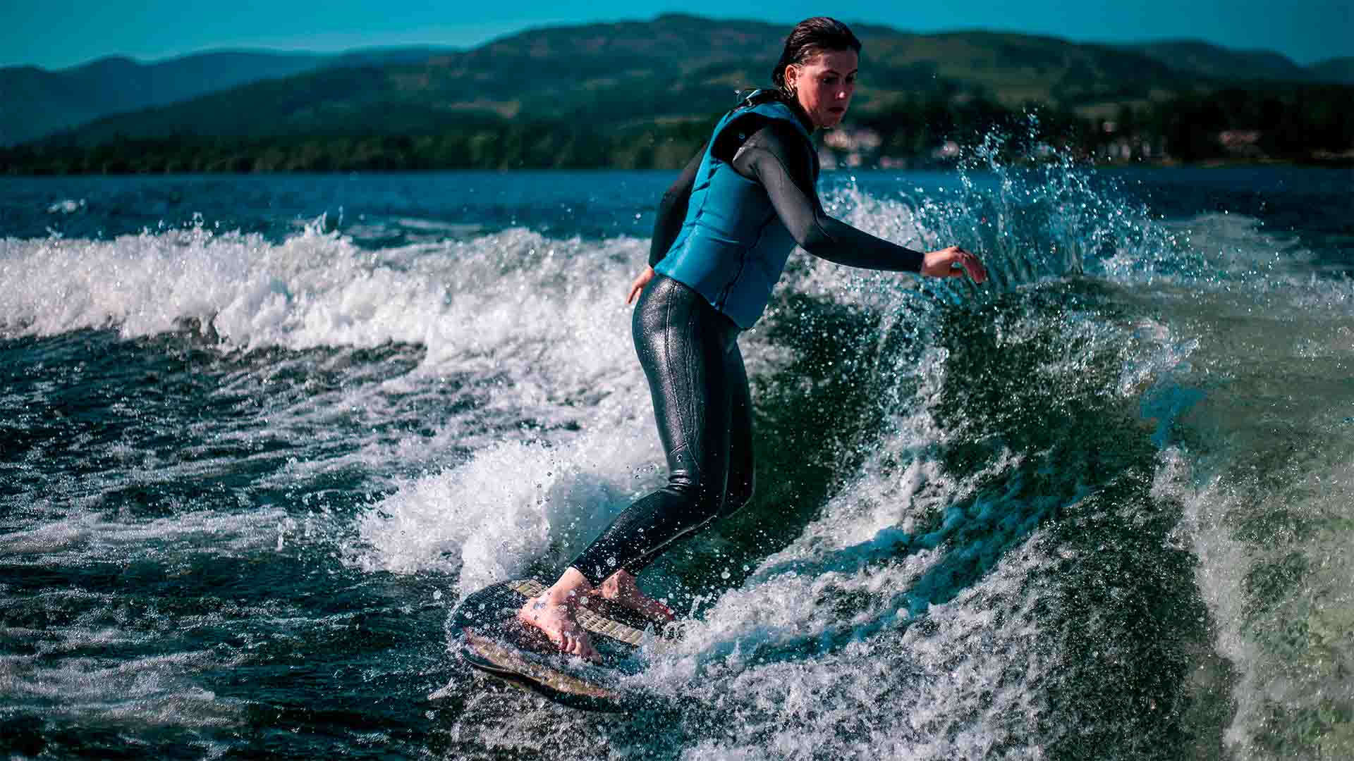 Young woman learning to wakesurf on Windermere