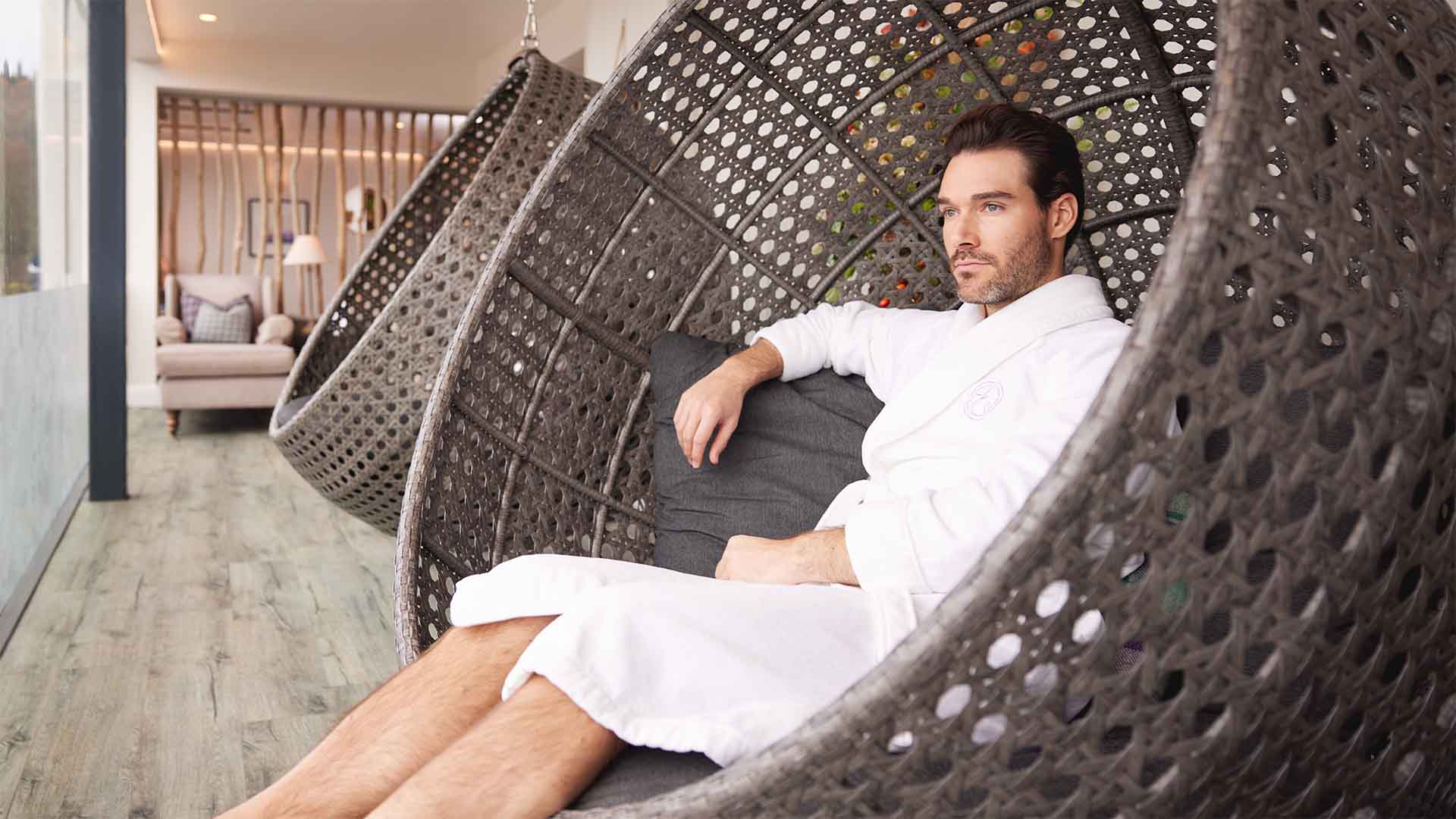 Young man sat in one of the suspended chairs in the spa