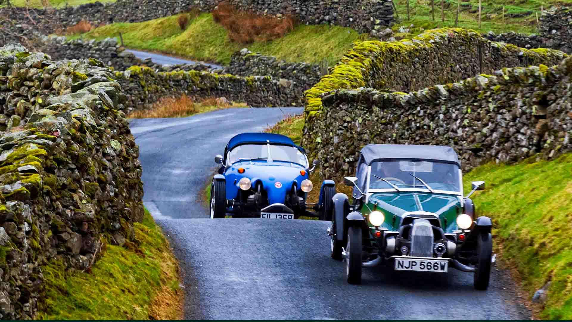 Two vintage cars ascend the struggle road from Ambleside