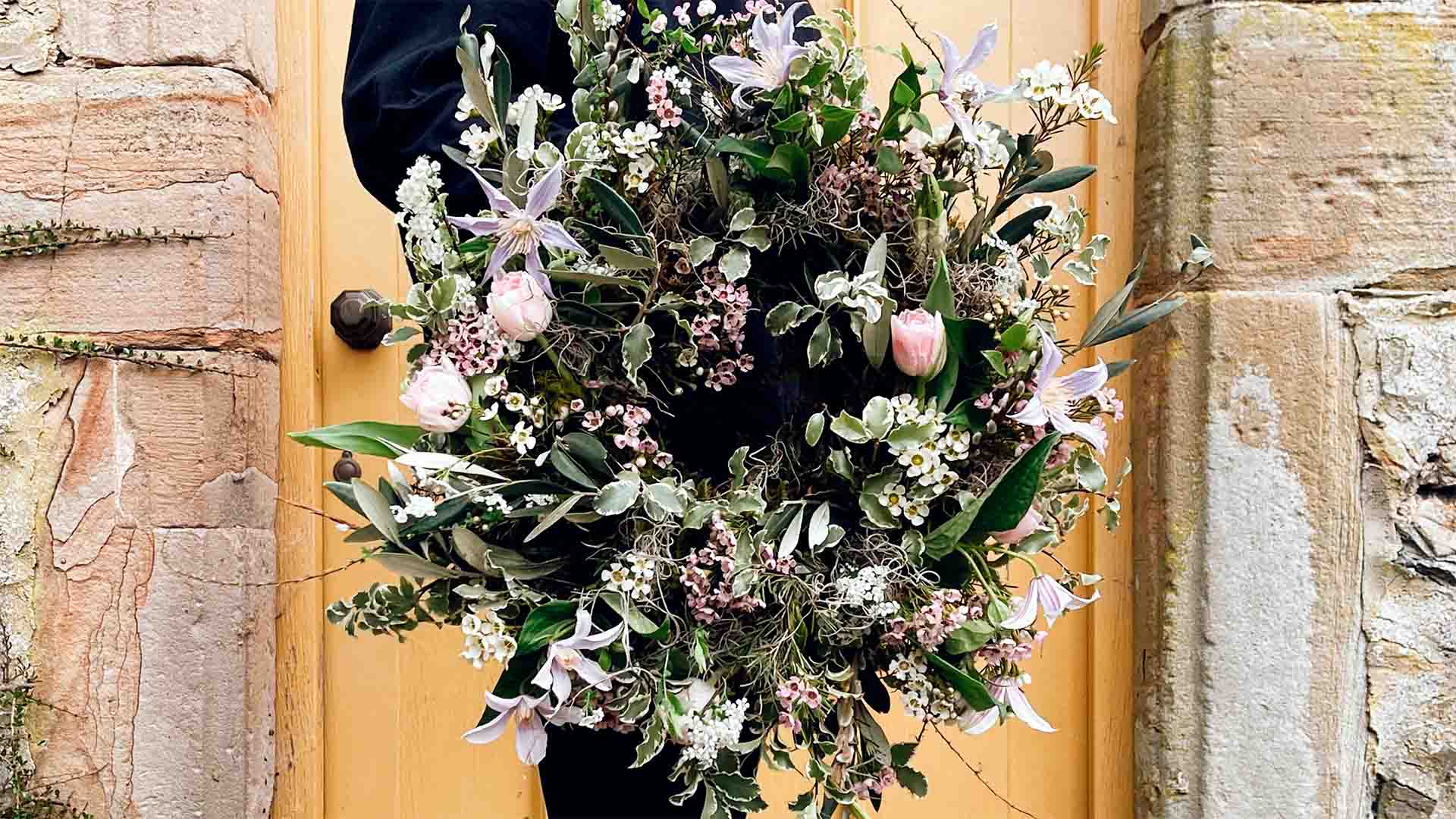 Woman holding a wreath by a door