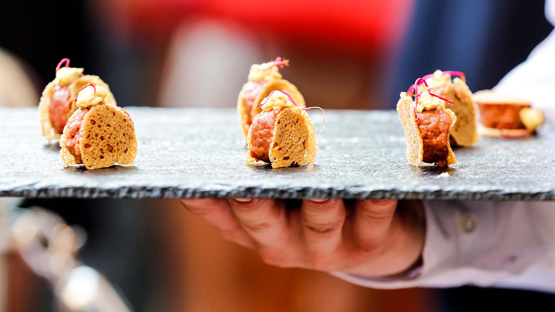Hand holding a slate tray with finger style buffet food atop