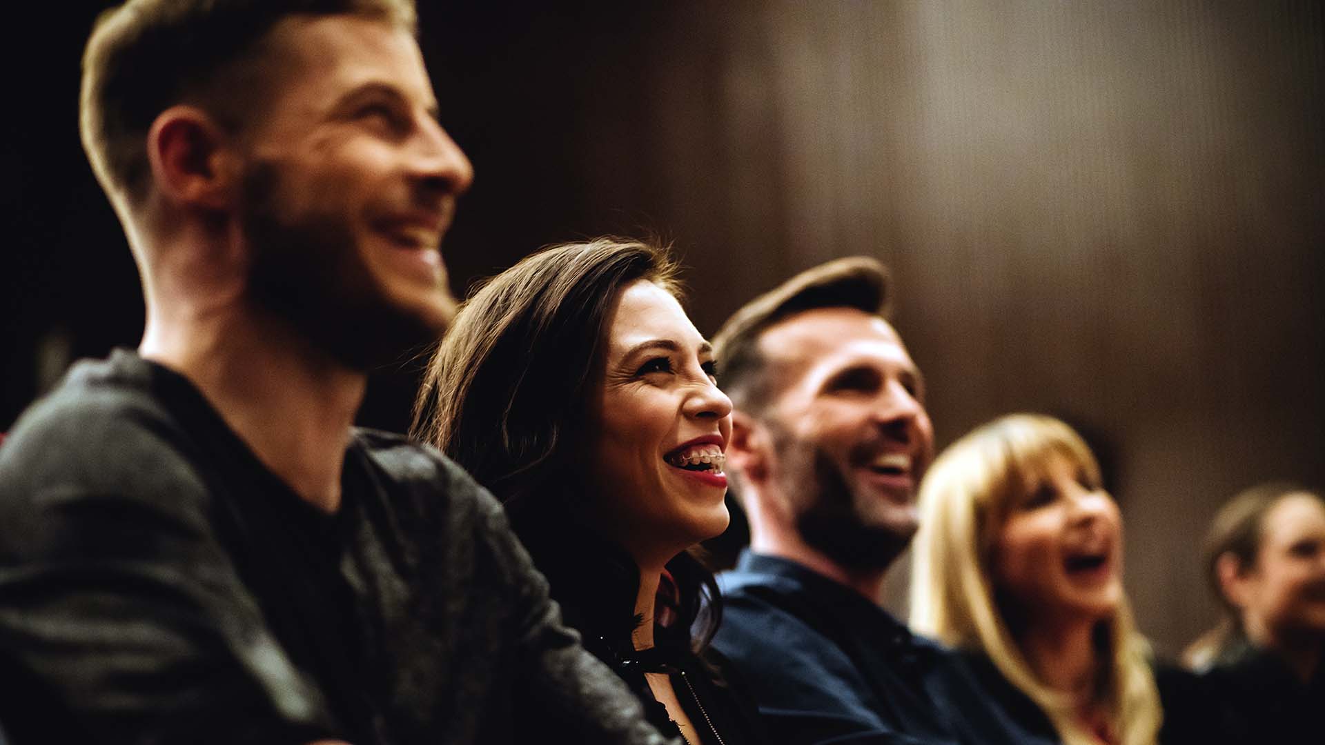 A group of young adults seated in line smiling at the presentation