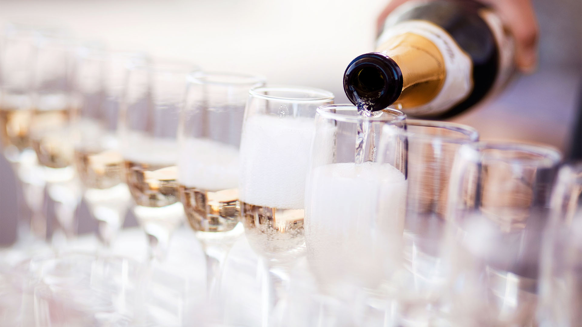 Pouring Champagne into rows of glasses