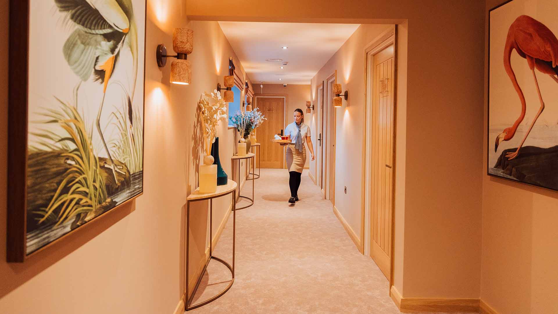 Young team member walking down the corridor with tray in hand outside the new treatment rooms