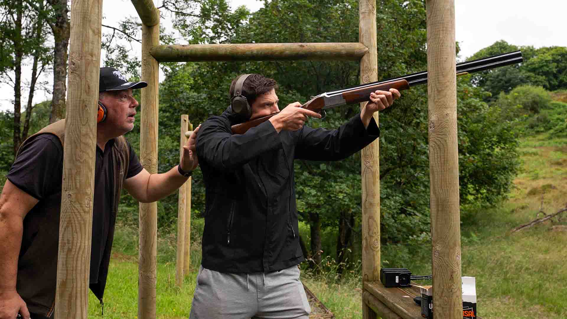 Young man being watched whilst shooting clays