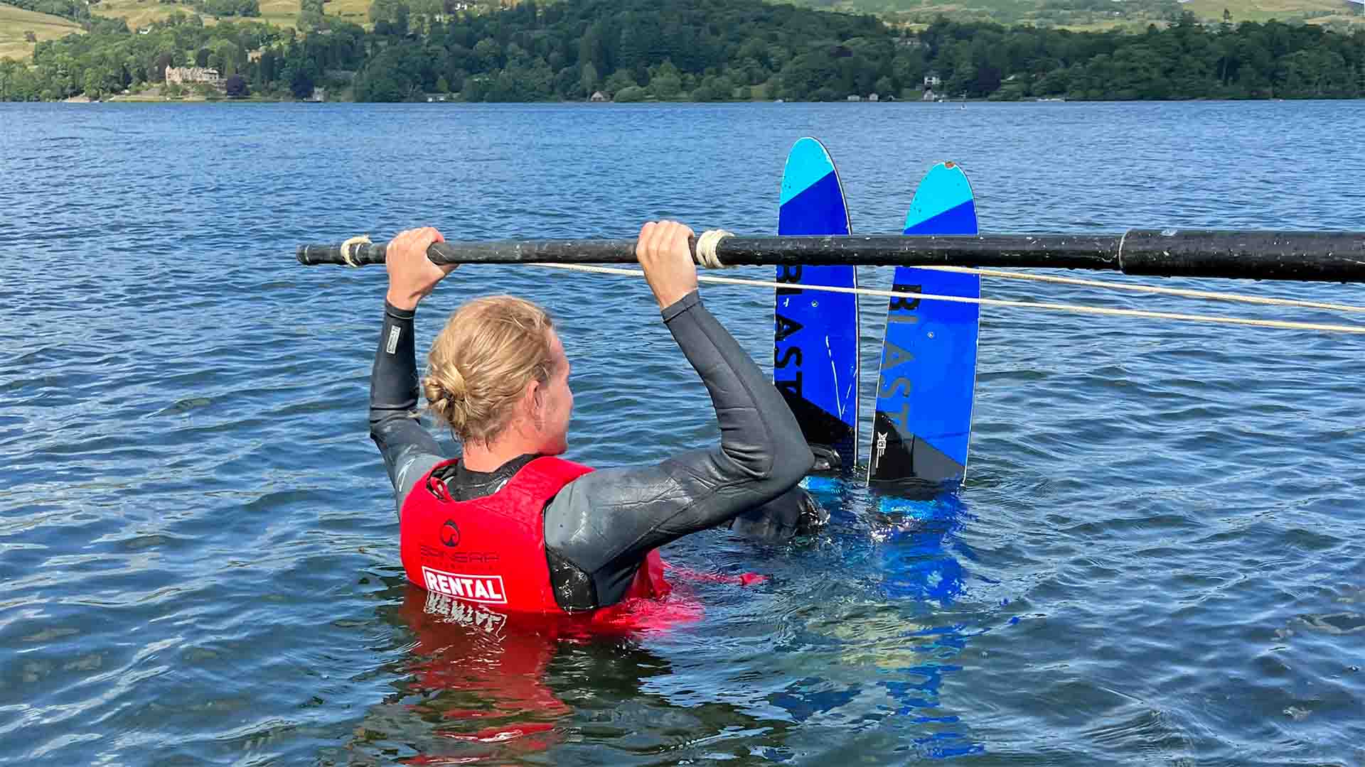 Young man in the waters of lake Windermere leaning how to waterski