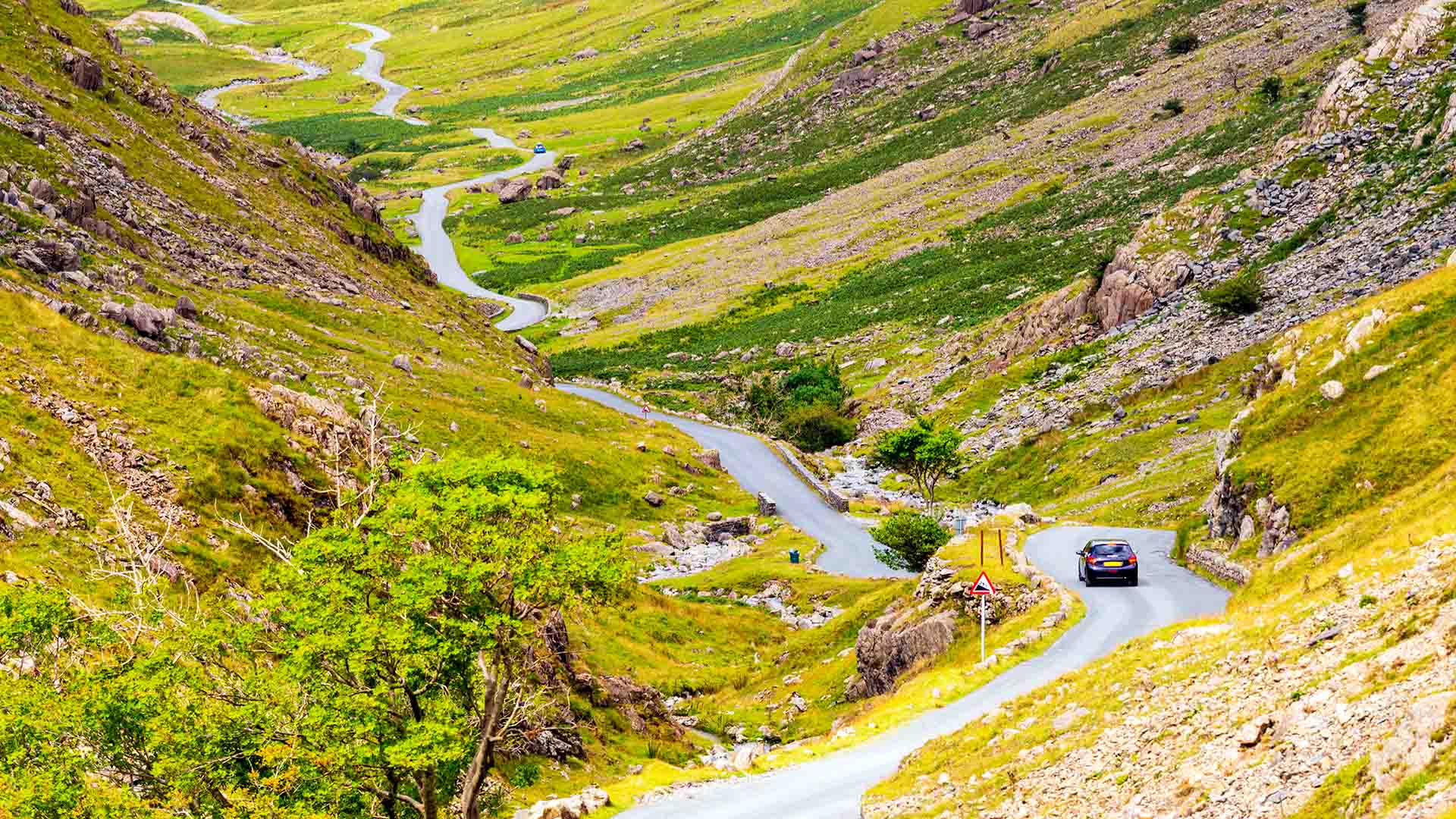 A car descending the winding road down Honister Pass