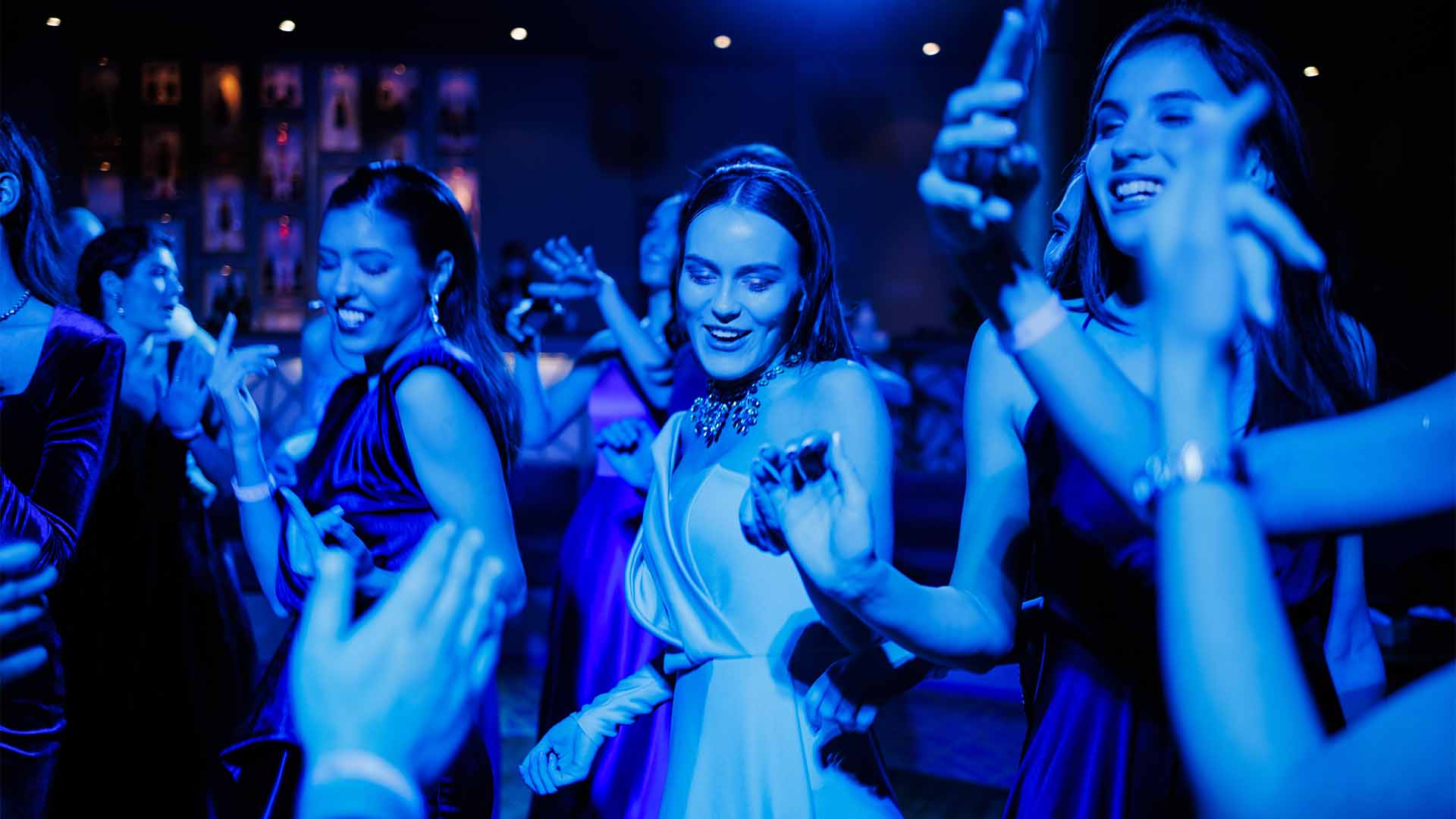 Young women dancing under blue electric lighting