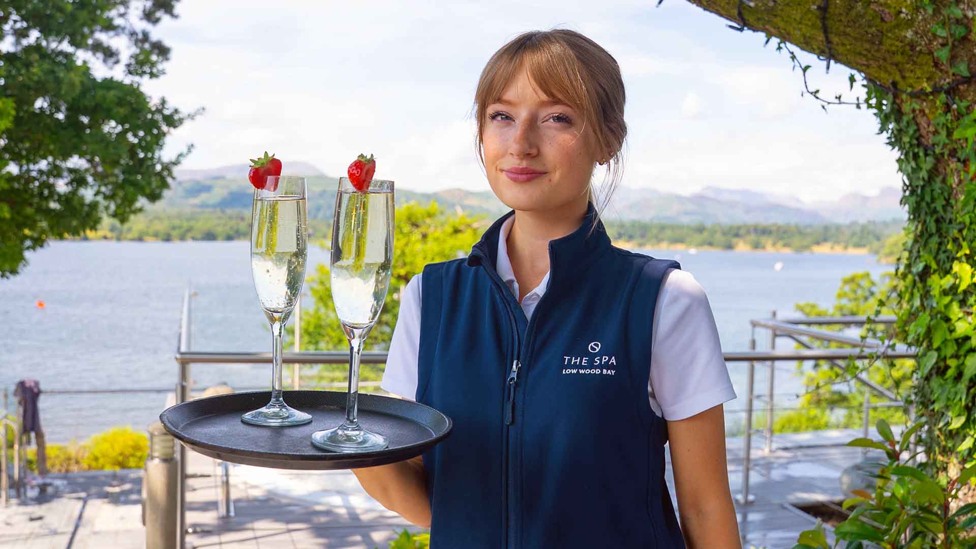 A spa tender holding a tray with 2 drinks