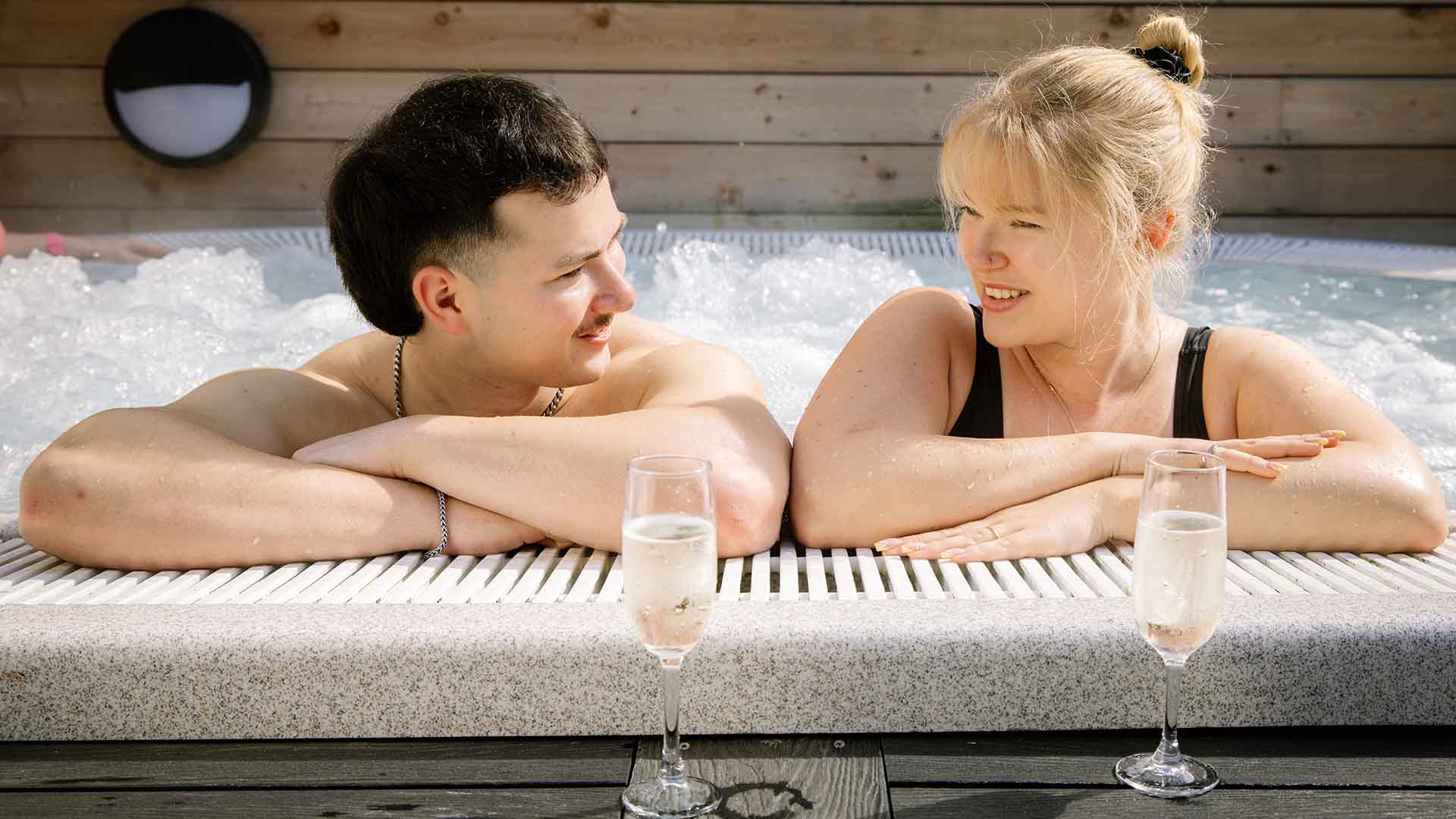 Young man and young woman in outdoor hot tub with prosecco glasses in Sandpiper Health Club at Lancaster House Hotel