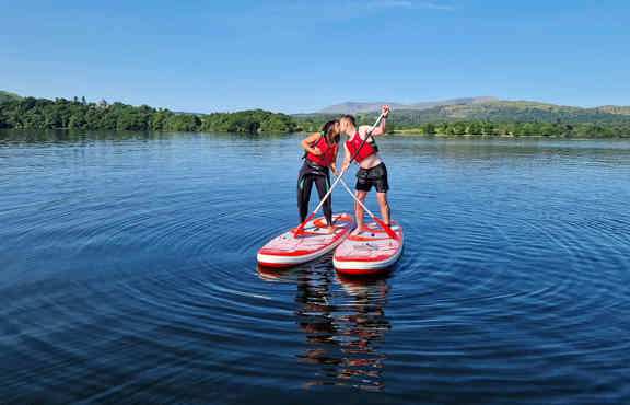 Couple stand up paddle boarding on Windermere