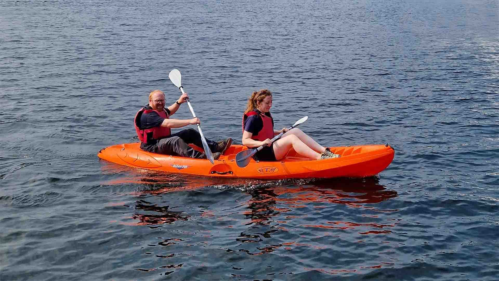 Two people sitting aboard a double sit-on-top hire kayak. Out on lake Windermere