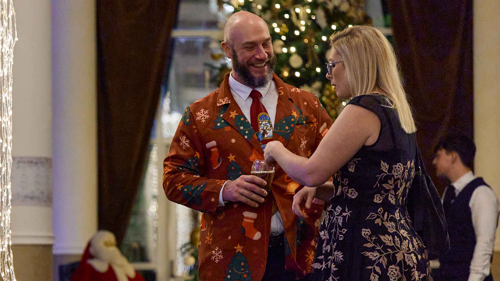 Couple stood talking in the gallery, man wearing a party suit