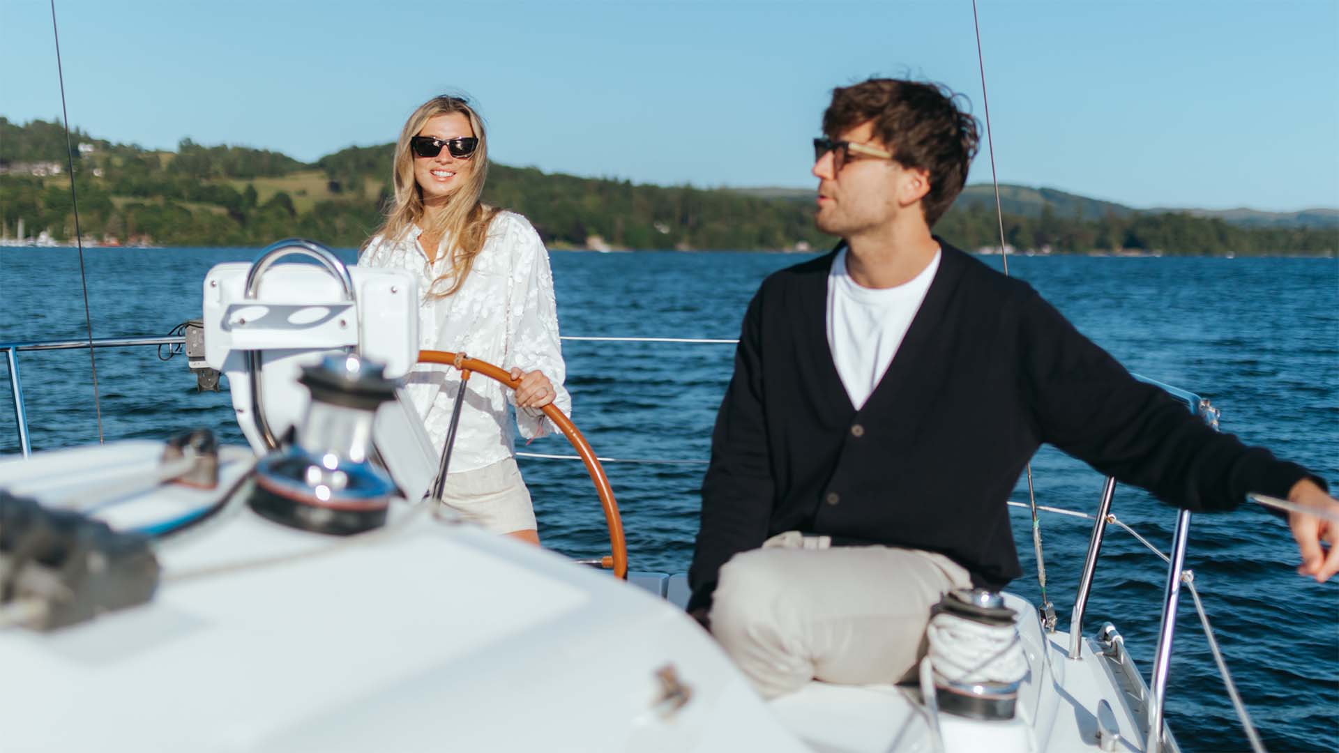 Couple at the helm of a chartered yacht out on lake Windermere