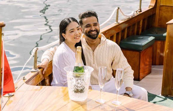 Two guests aboard the Winander launch with a bottle of chilling Champagne by their side
