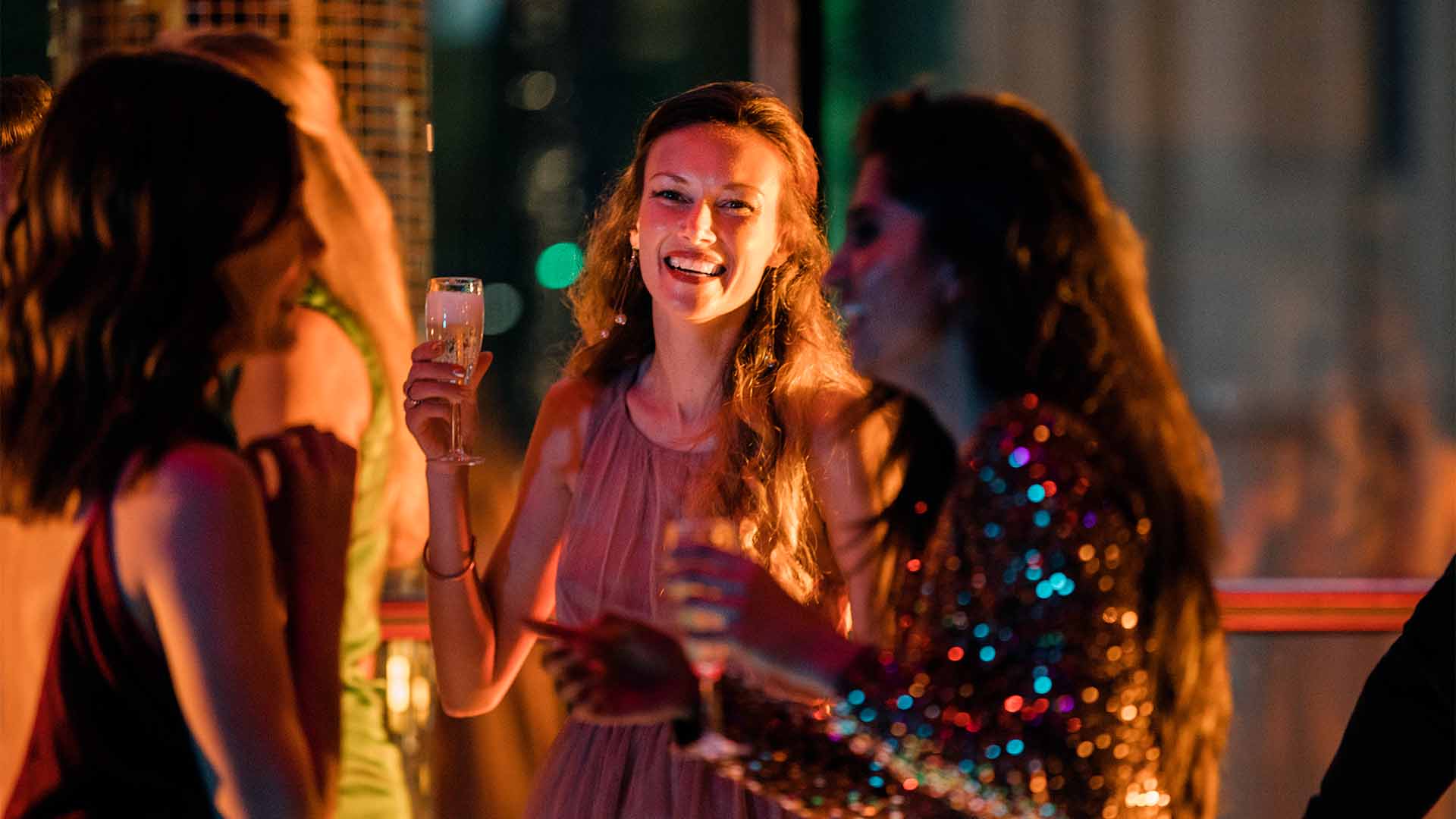 Group of young women dancing holding drinks glasses