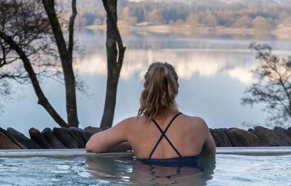 Young woman in the Fellside Pool looking out over a wintry Langdale Pikes