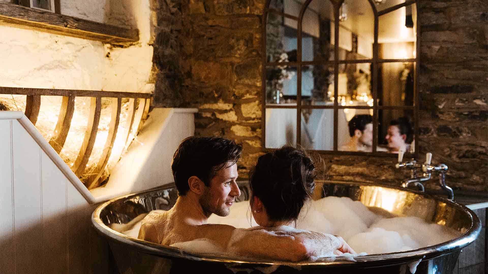 Couple sat in the deep bath in the hideaway treatment room