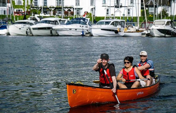 Three people in an open canoe on lake Windermere