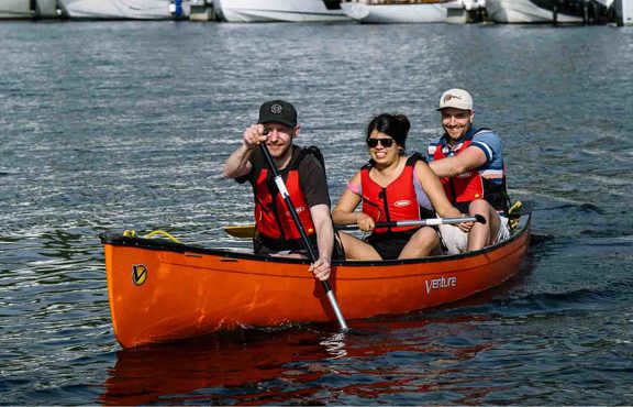 Three people in a hired open canoe on lake Windermere