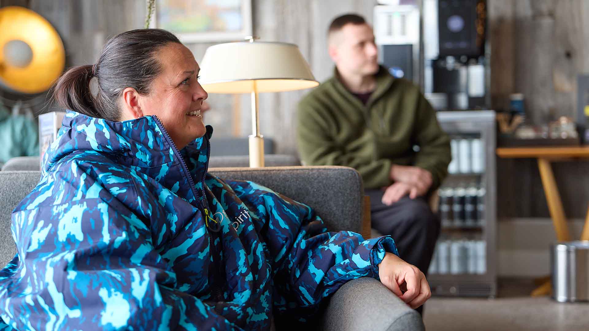 Woman in a blue camouflage dryrobe listening to a briefing