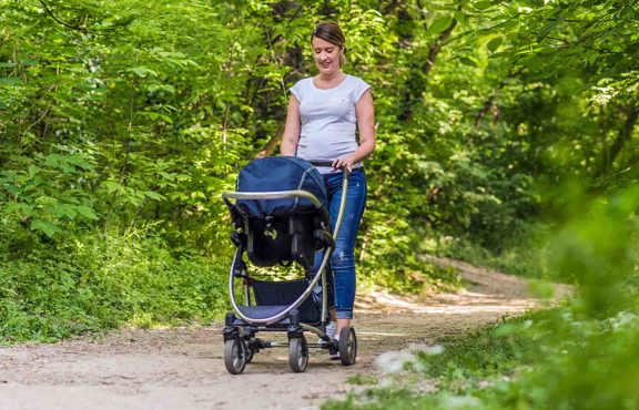 Lady waking a pram in woodland