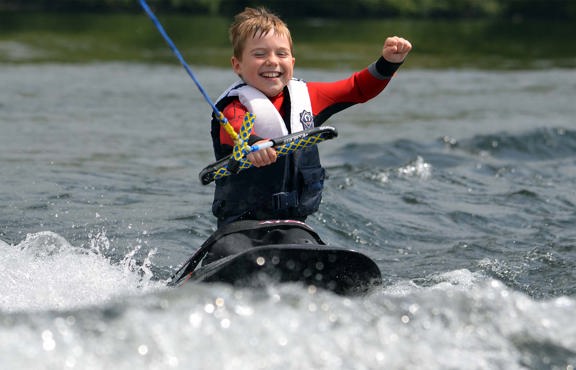 Young boy enjoying kneeboarding on lake Windermere