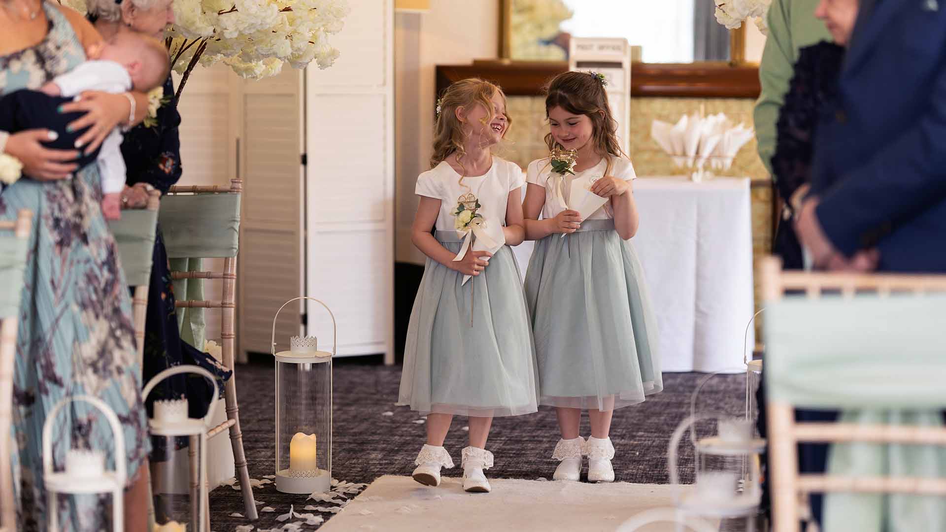 Two bridesmaids walking down the aisle in the Buckley Room at Low Wood Bay