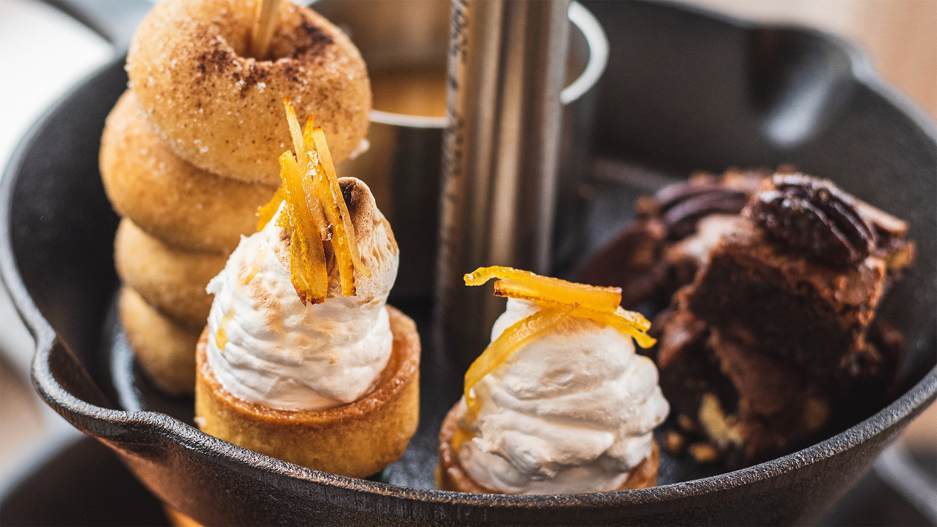 Lemon meringue pies, chocolate brownies and a stack of donuts on a skillet