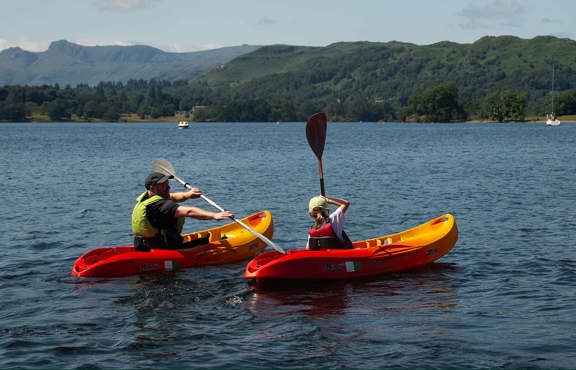 Man and child paddling hired, sit-on-top kayaks on lake Windermere