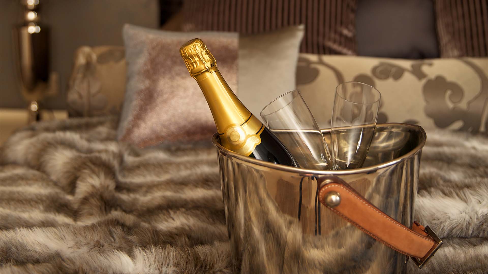 Bottle of Prosecco with glasses in an ice bucket on a bed